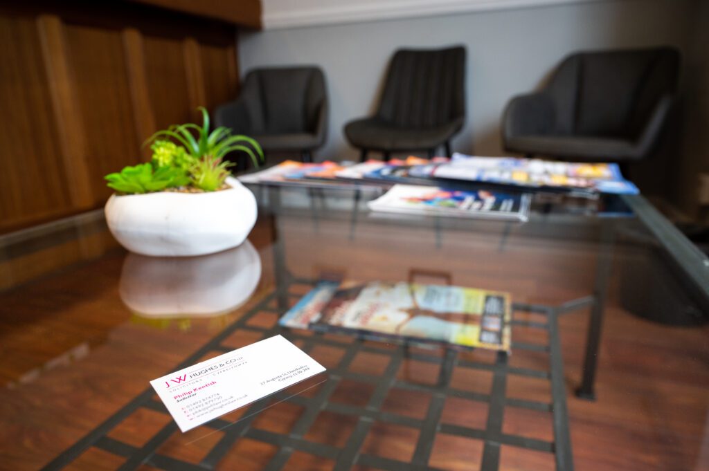 Image of our Llandudno reception waiting area, glass coffee table and business card.